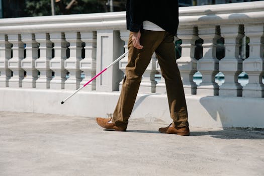 A blind person walking with a cane on a sidewalk, showcasing independence and mobility.