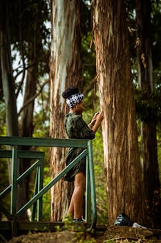 A woman enjoys the serene beauty of a park in Kenya, surrounded by tall trees and lush nature.