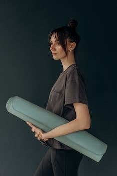 A young woman holding a yoga mat, ready for her wellness routine indoors.