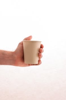 Close-up of a hand holding an eco-friendly paper cup, emphasizing sustainability.