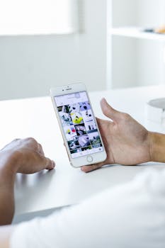 Close-up of hands holding a smartphone displaying a gallery of images in bright indoor setting.