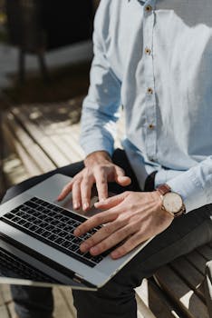 Freelancer sitting outdoors, typing on a laptop, enjoying remote work flexibility.