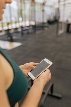 Woman checks timer on smartphone while working out in gym.