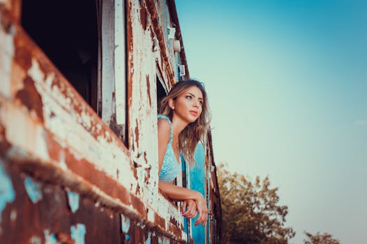 Young woman gazes out a rusty train window, embracing the spirit of travel and adventure.