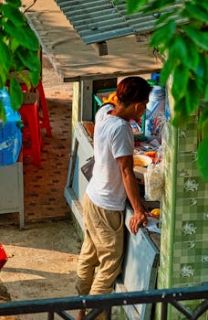 A vendor in Jakarta tends to a small street market stall, showcasing urban commerce.