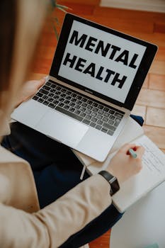 A woman engaging in an online mental health session on a laptop.