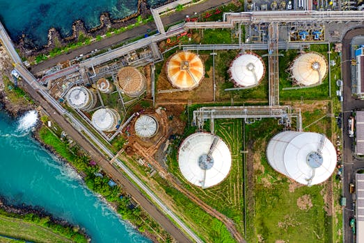 Aerial view of an industrial complex near a river in Banten, Indonesia, showcasing storage tanks.