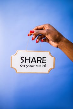 Close-up of a hand holding a 'Share on your social' sign on a vibrant blue backdrop.