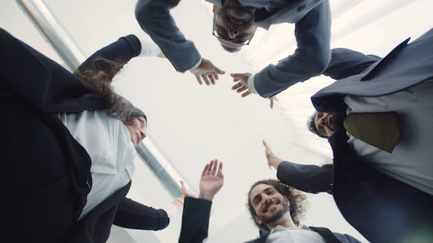 Low-angle shot of a diverse business team celebrating unity and success indoors.