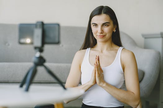 Woman practicing yoga at home while recording with smartphone camera.