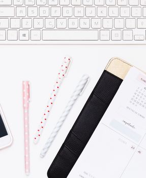 Flat lay of a tidy workspace featuring pens, planner, and keyboard, ideal for productivity.