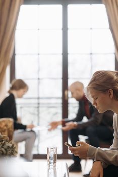 Three adults interacting with smartphones in a cozy indoor setting.